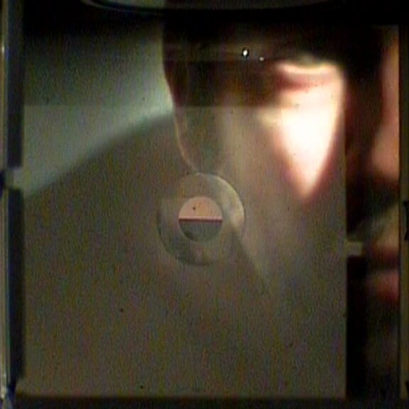Through the viewfinder: the face half in shadow on the ground glass, the focusing circle below the eye