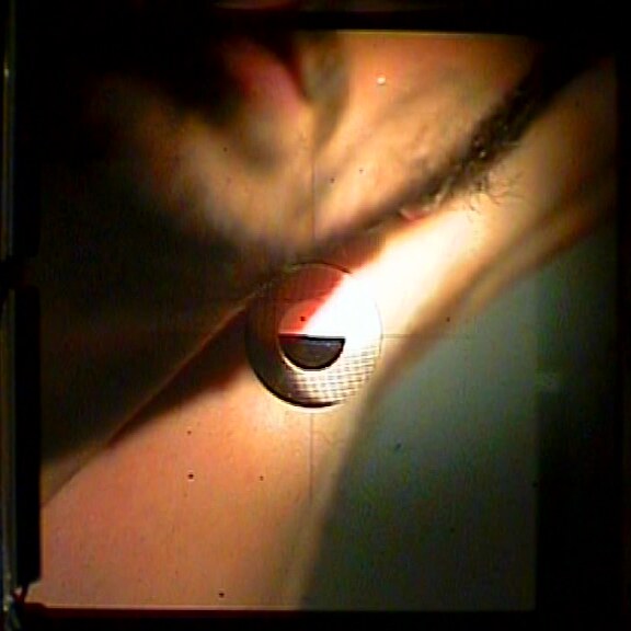 Through the viewfinder: the jaw and throat on the ground glass in red light, the focusing circle at the neck