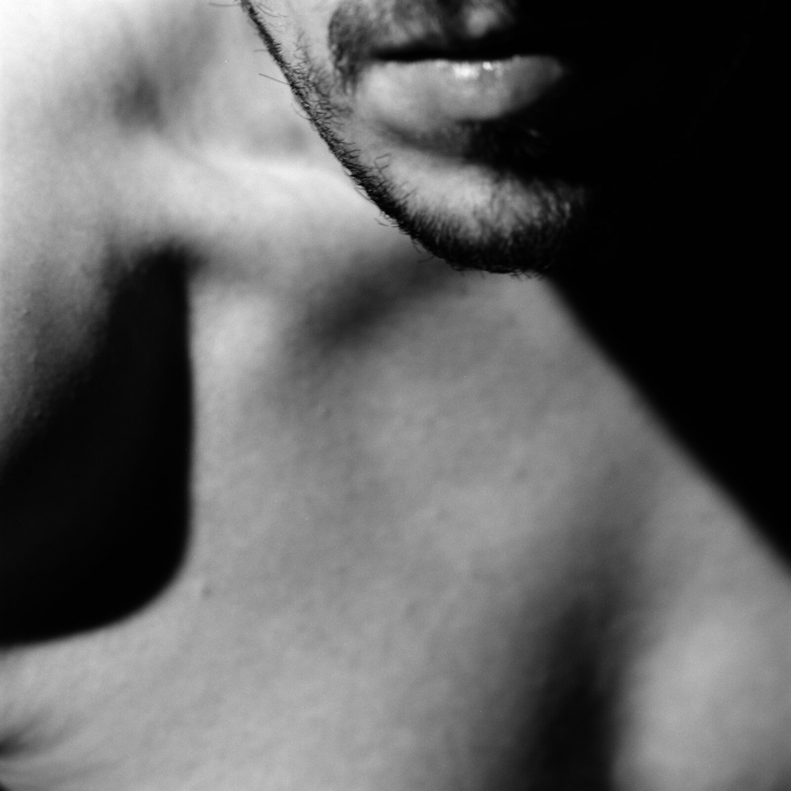 A mouth and a bearded chin above the collarbone and the chest