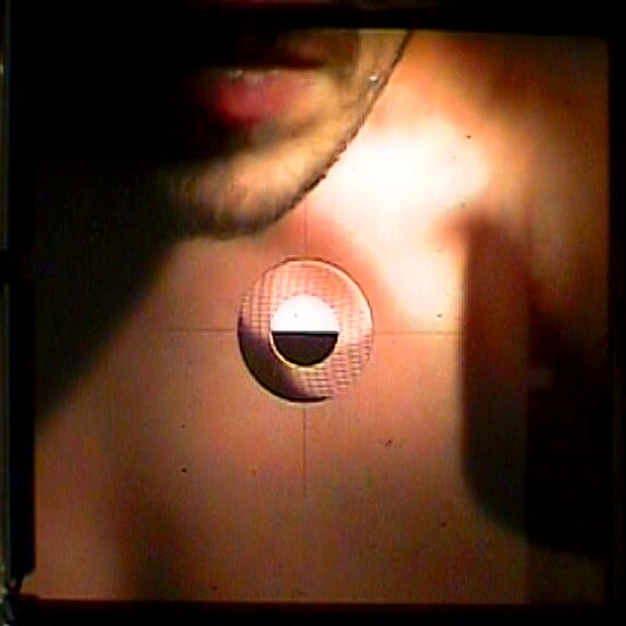 Through the viewfinder: the mouth, chin and chest on the ground glass, lit warm