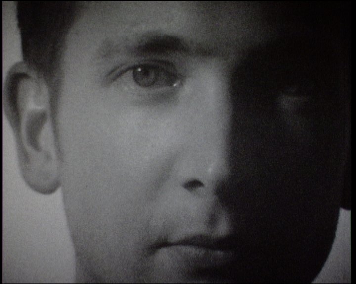 A young man's face close to the lens, one eye in light, the other side of the face in shadow