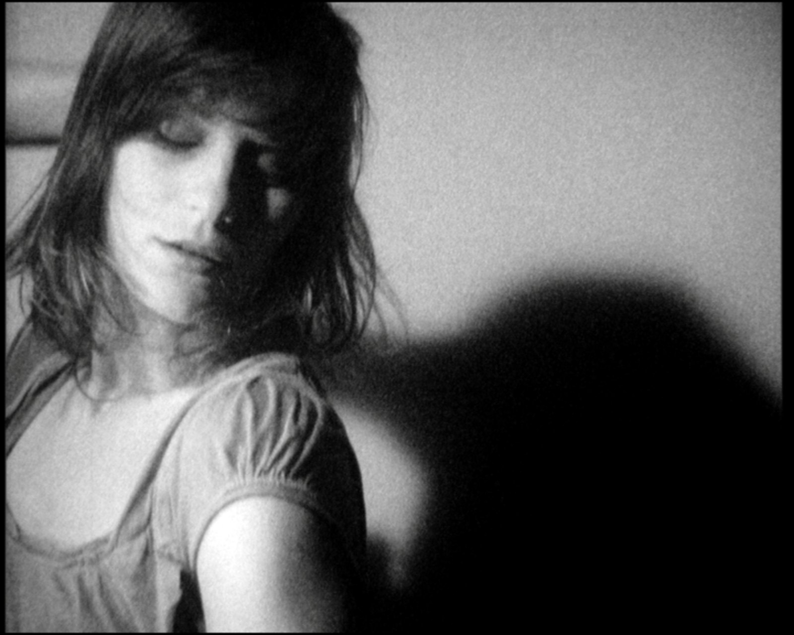 Her head tilted down to the left, eyes closed, the puffed sleeve at the shoulder, her shadow thrown on the wall behind