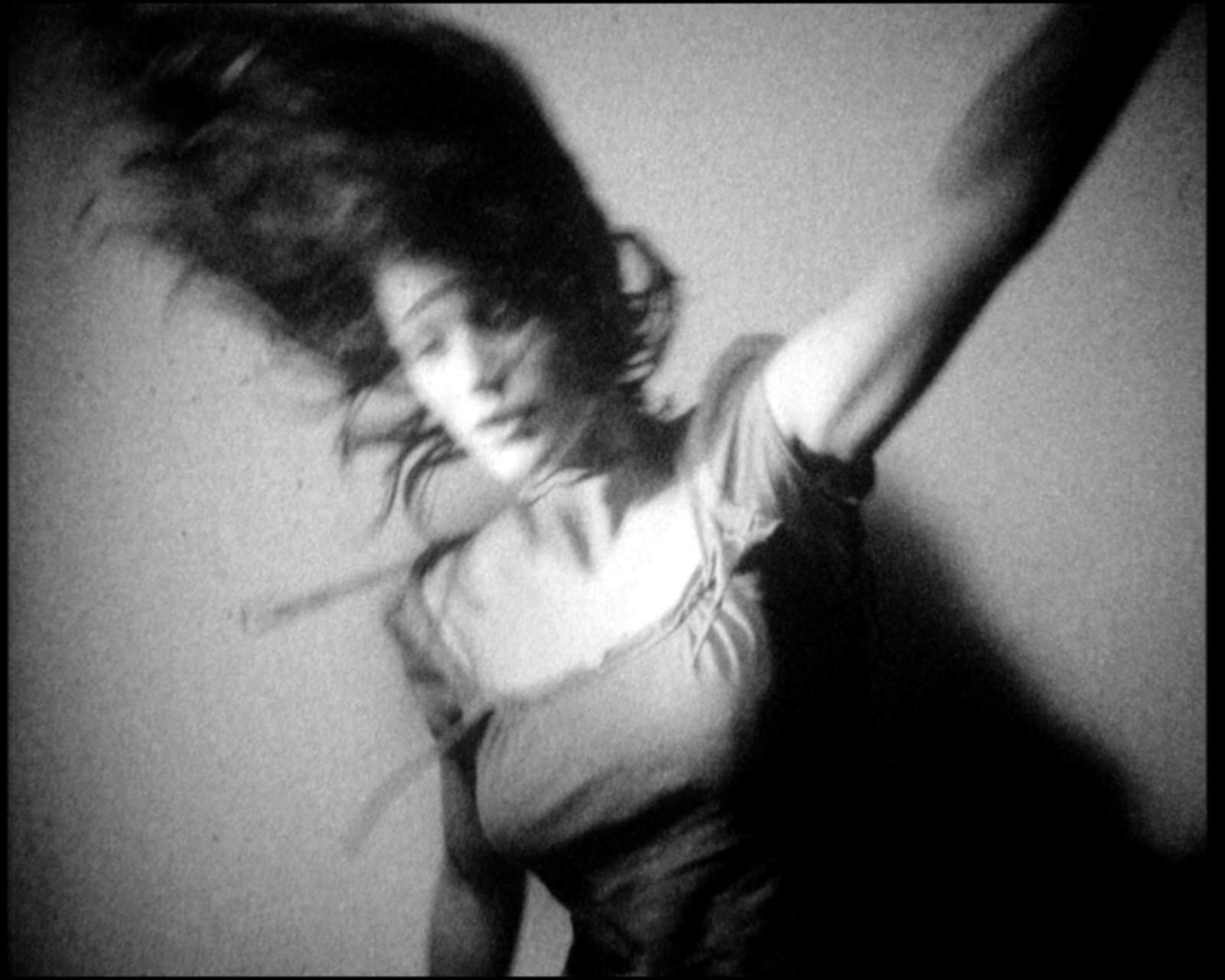 Head and hair thrown back to the left, one arm raised high, the body a blur of light