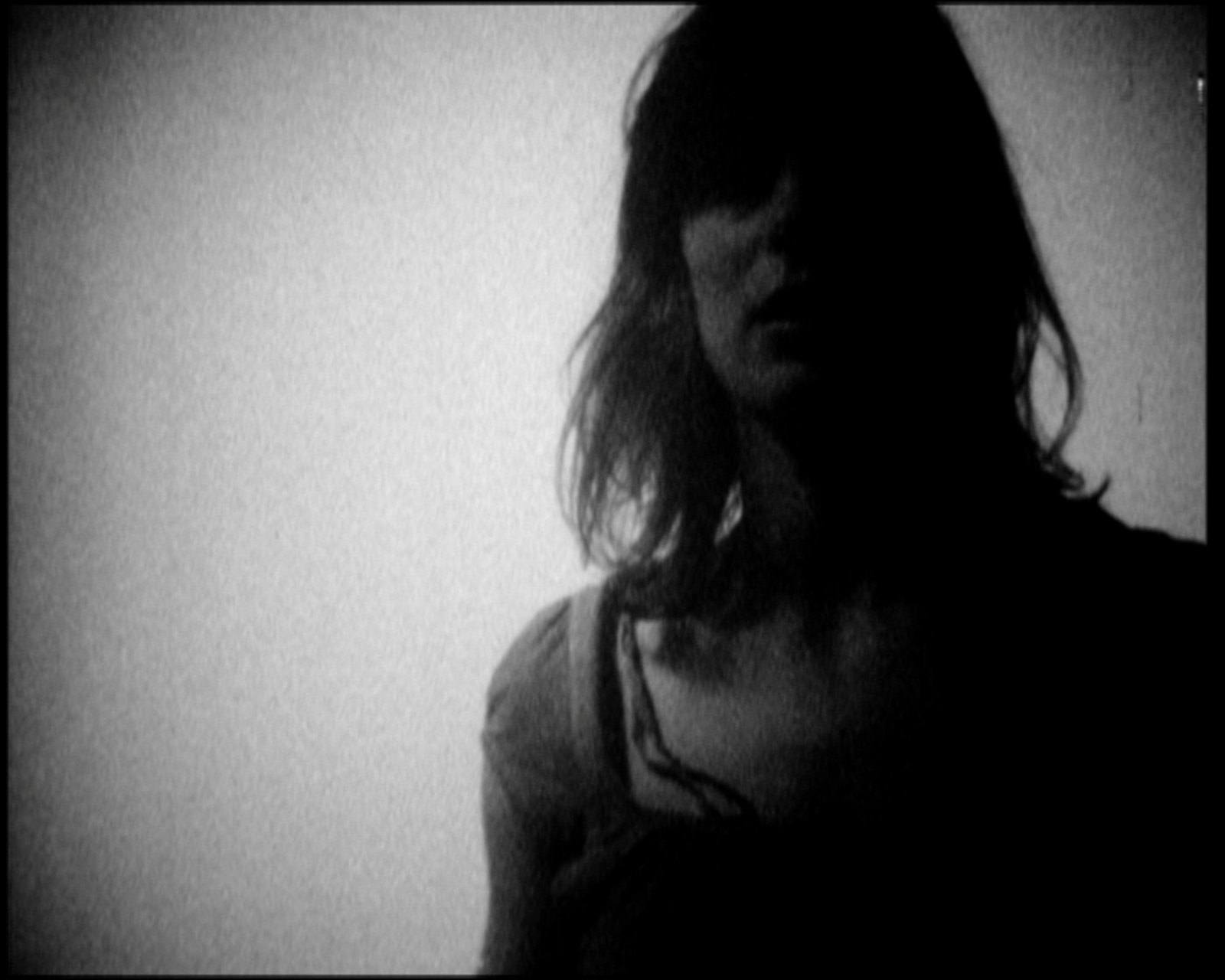 Her figure dark against the bright wall, the face in shadow, hair down