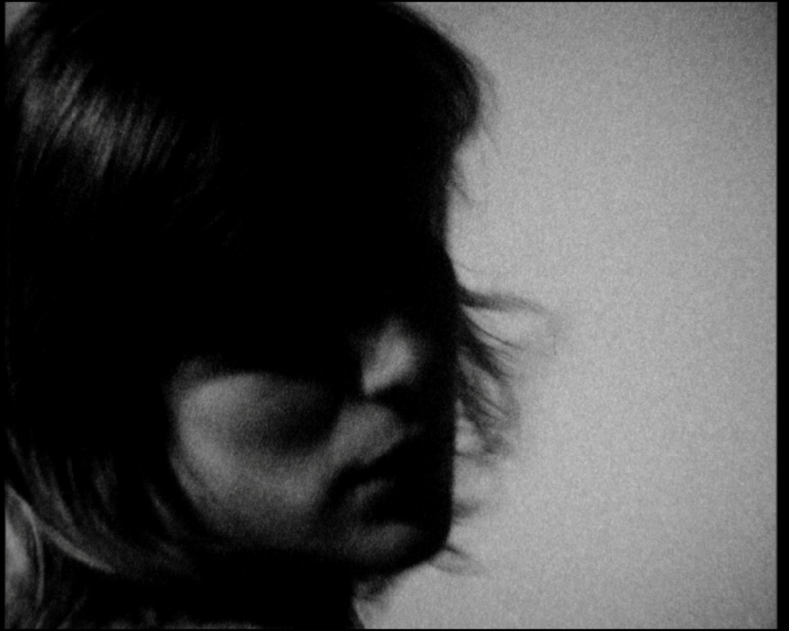 Her head in profile close to the lens, the hair dark, the shoulder a blur