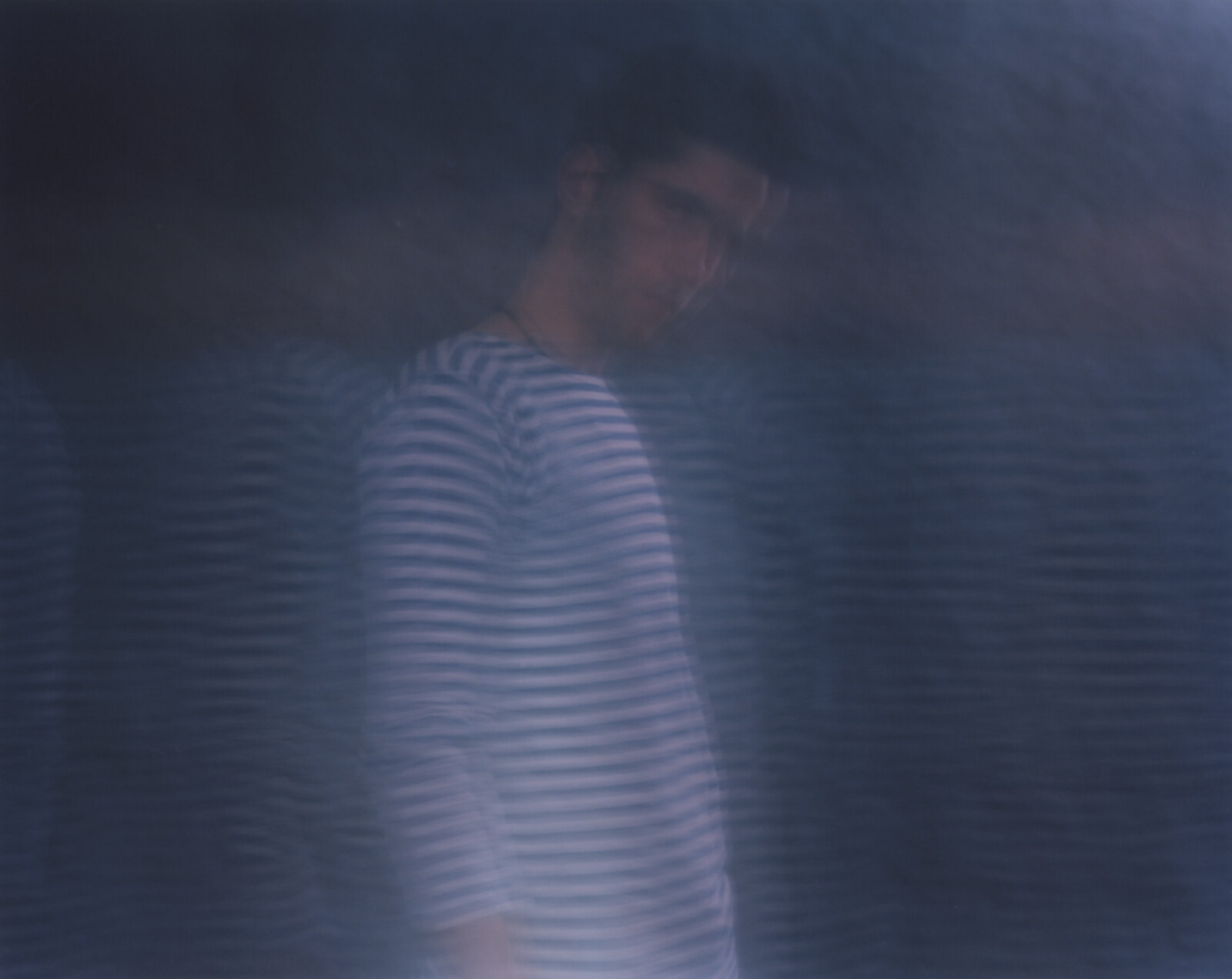 The figure standing left of centre, the striped shirt breaking into fine ripples that carry on across the pale field beside it