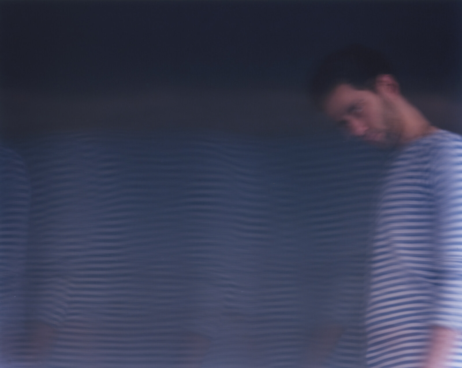 The head resolving almost sharply at the right edge, the rest of the body drawn out to the left as a wide field of horizontal ripples