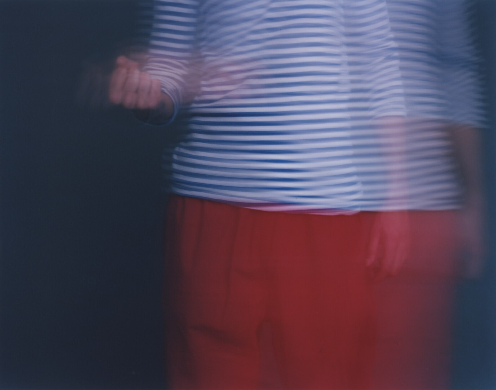 A striped torso standing at the right, the fist carried out to the left, red trousers below, the ground reading almost black