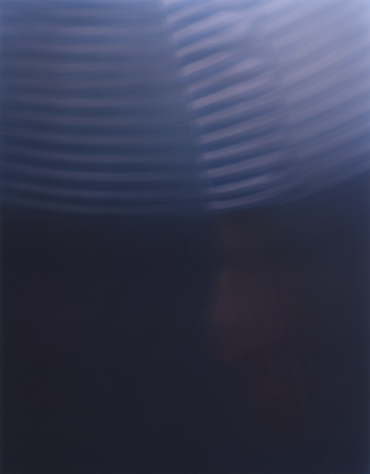 A near-dark frame, the movement surviving only as pale striped ripples across the upper half