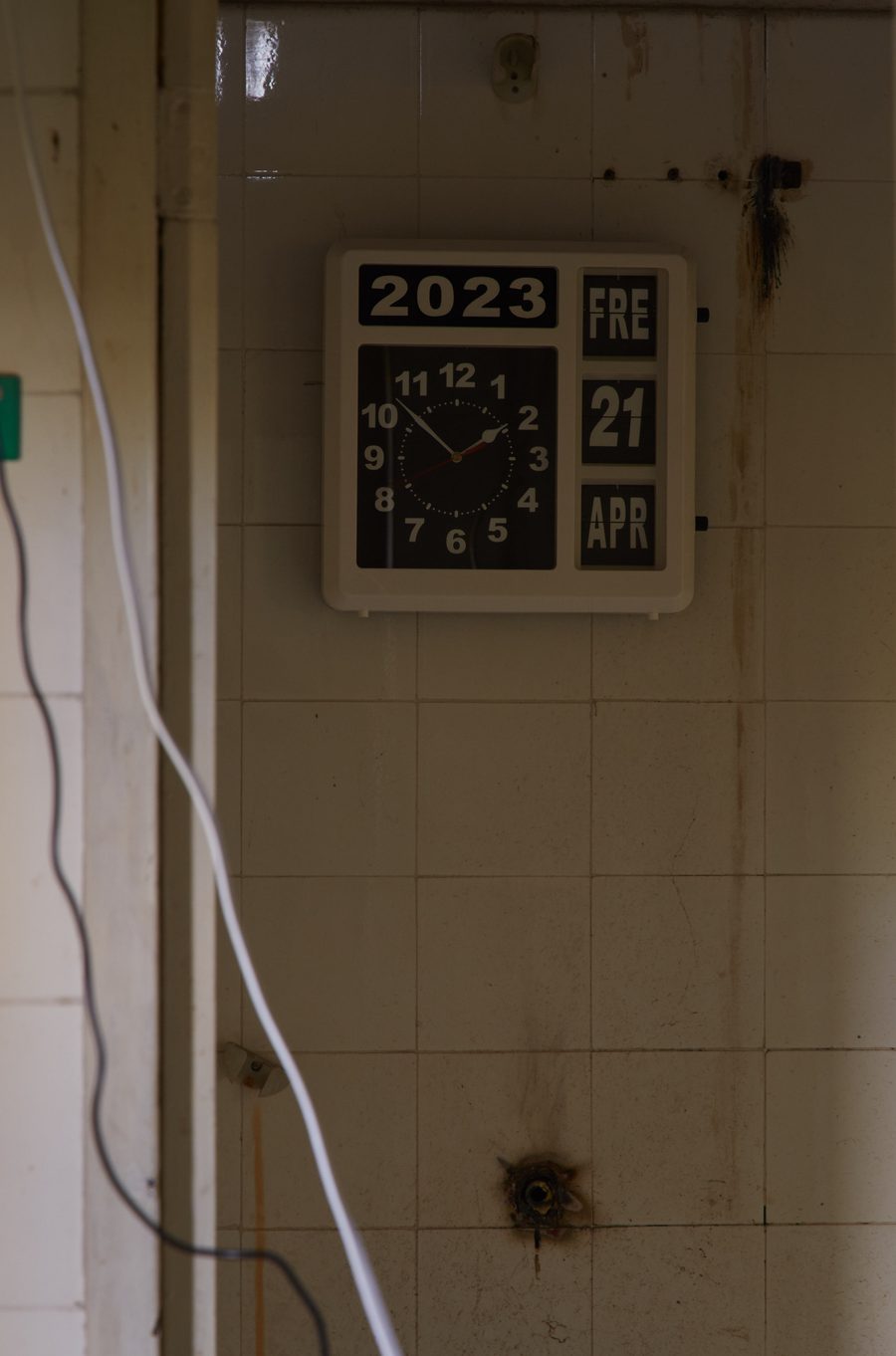 A flip-clock on a tiled wall showing the year 2023 and Friday 21 April