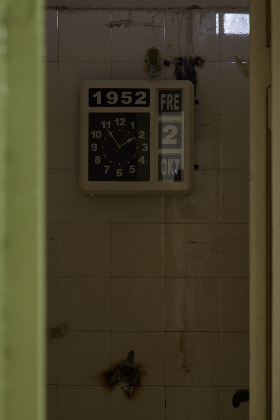 A flip-clock on a tiled wall showing the year 1952 and an October date