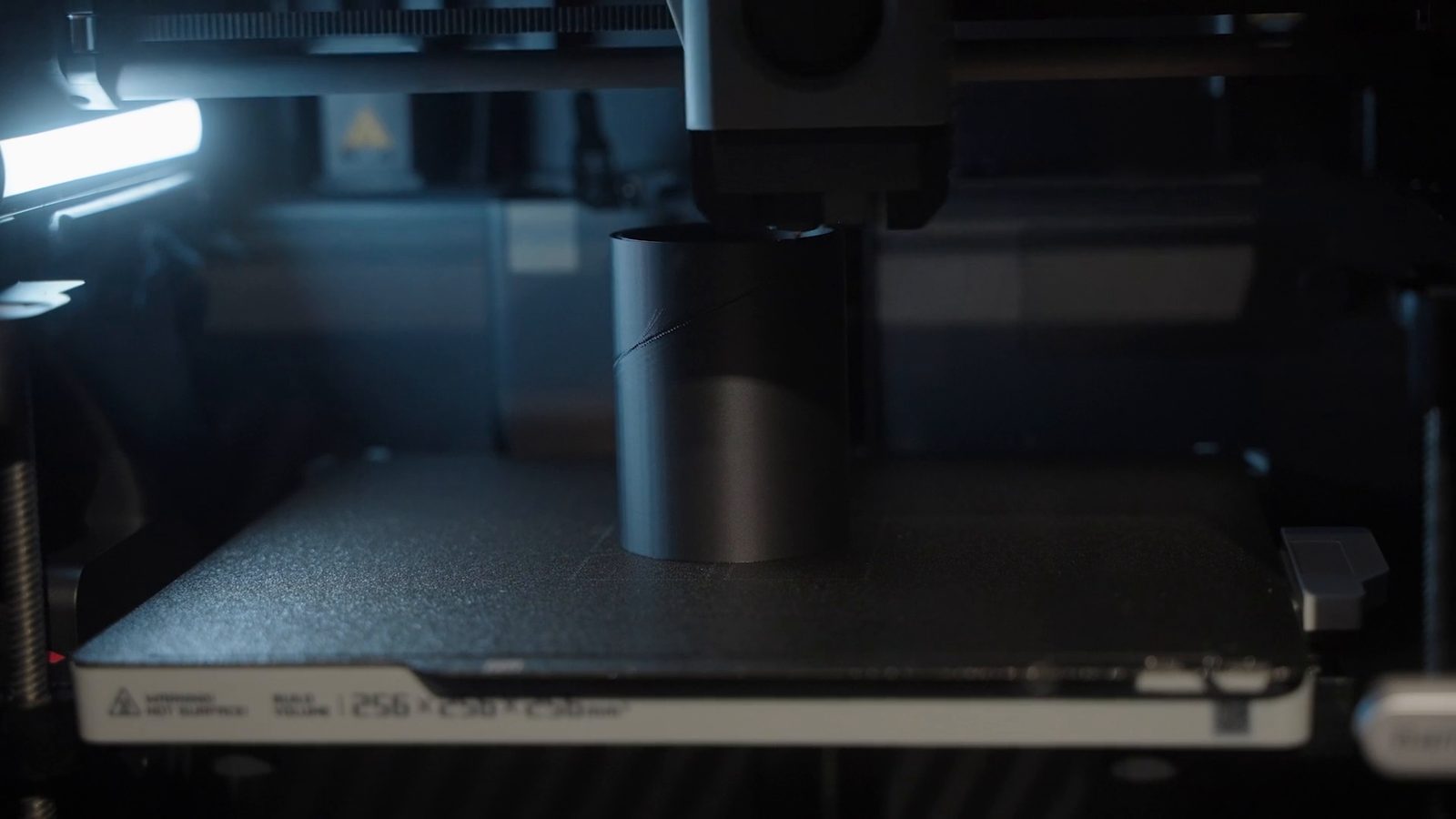 Inside the printer: a black cylinder partly printed on the plate, the print head at its rim, a diagonal groove across its wall