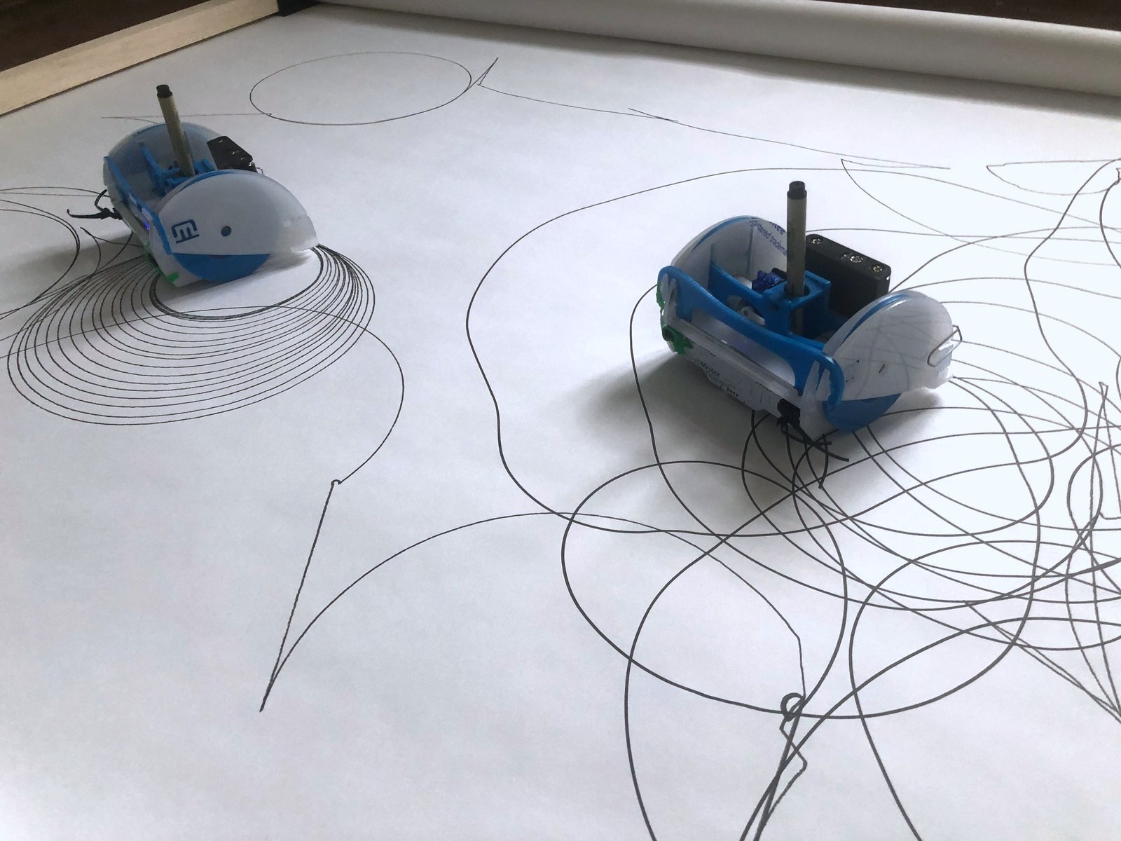 The two robots on the last band: one at the left inside its ring of concentric circles, the other at the right in a thicket of overlapping loops