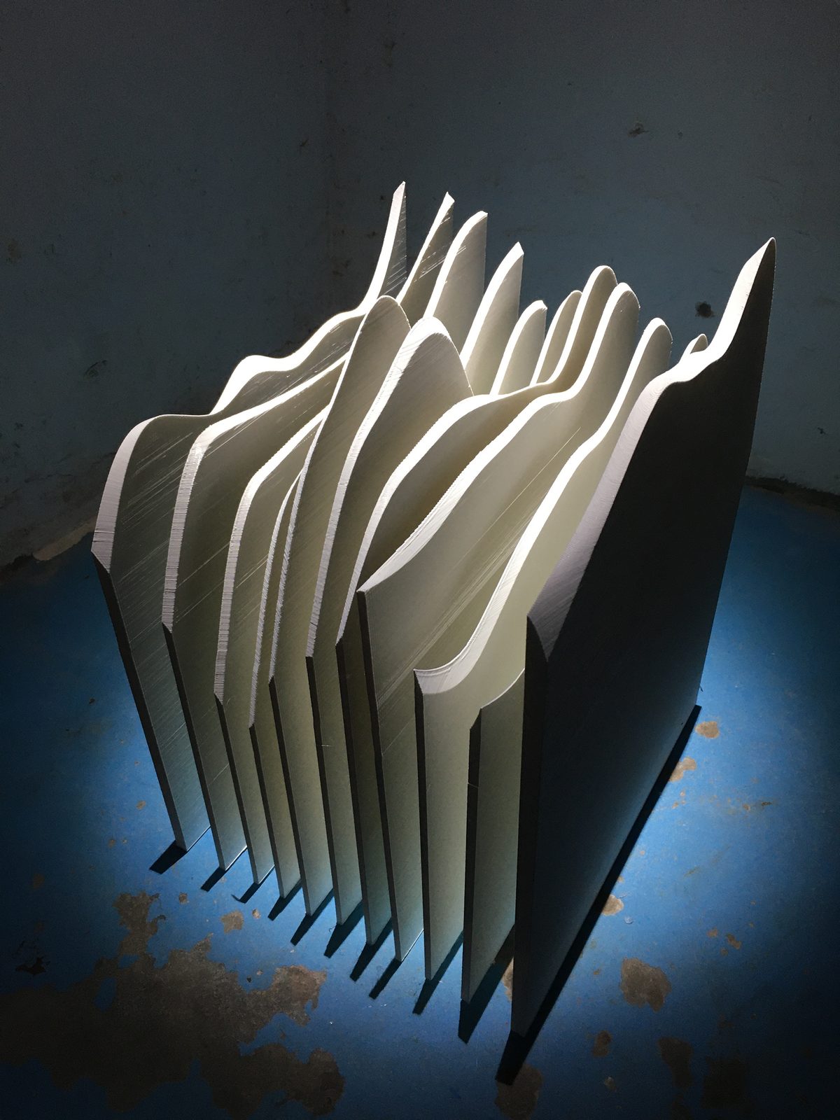 The sculpture on a floor washed with blue light, its slices catching the light along their edges